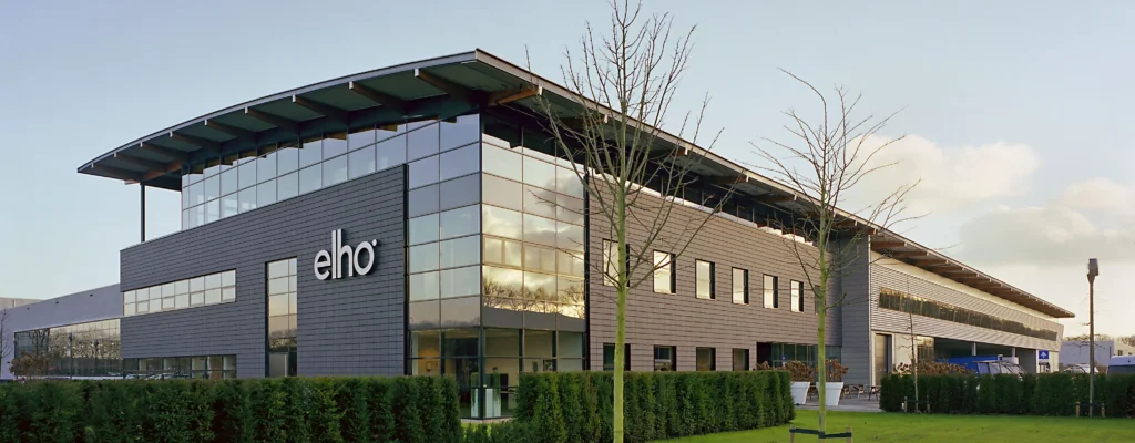 Modern office building with "elho" branding in Tilburg, featuring large windows and a landscaped exterior.