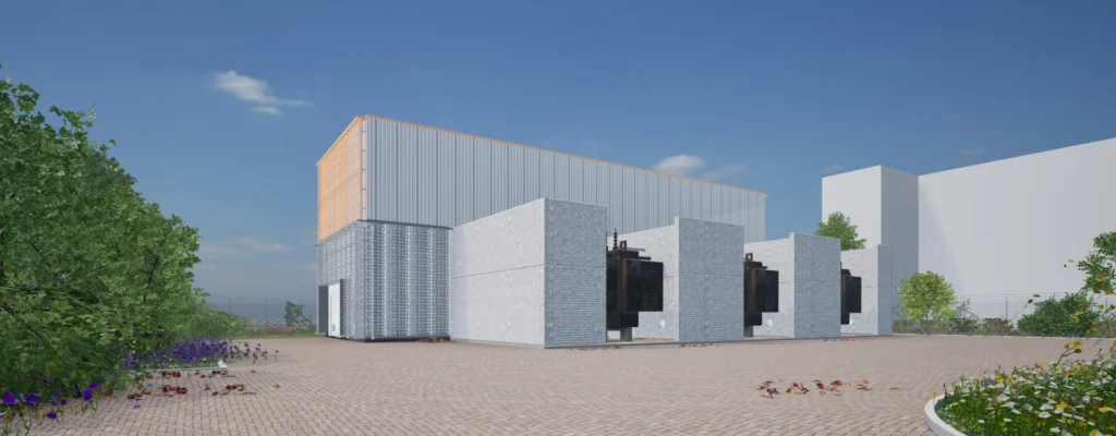Modern industrial building with gray and orange sections, surrounded by greenery, viewed from the southwest.
