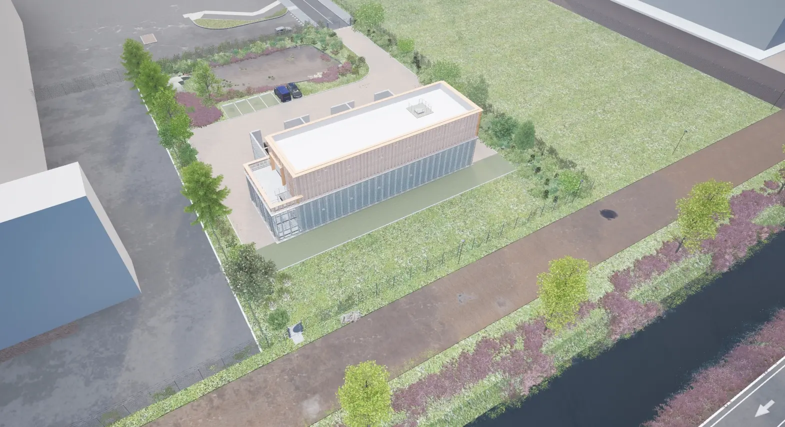Aerial view of a modern rectangular building surrounded by greenery and parking spaces.