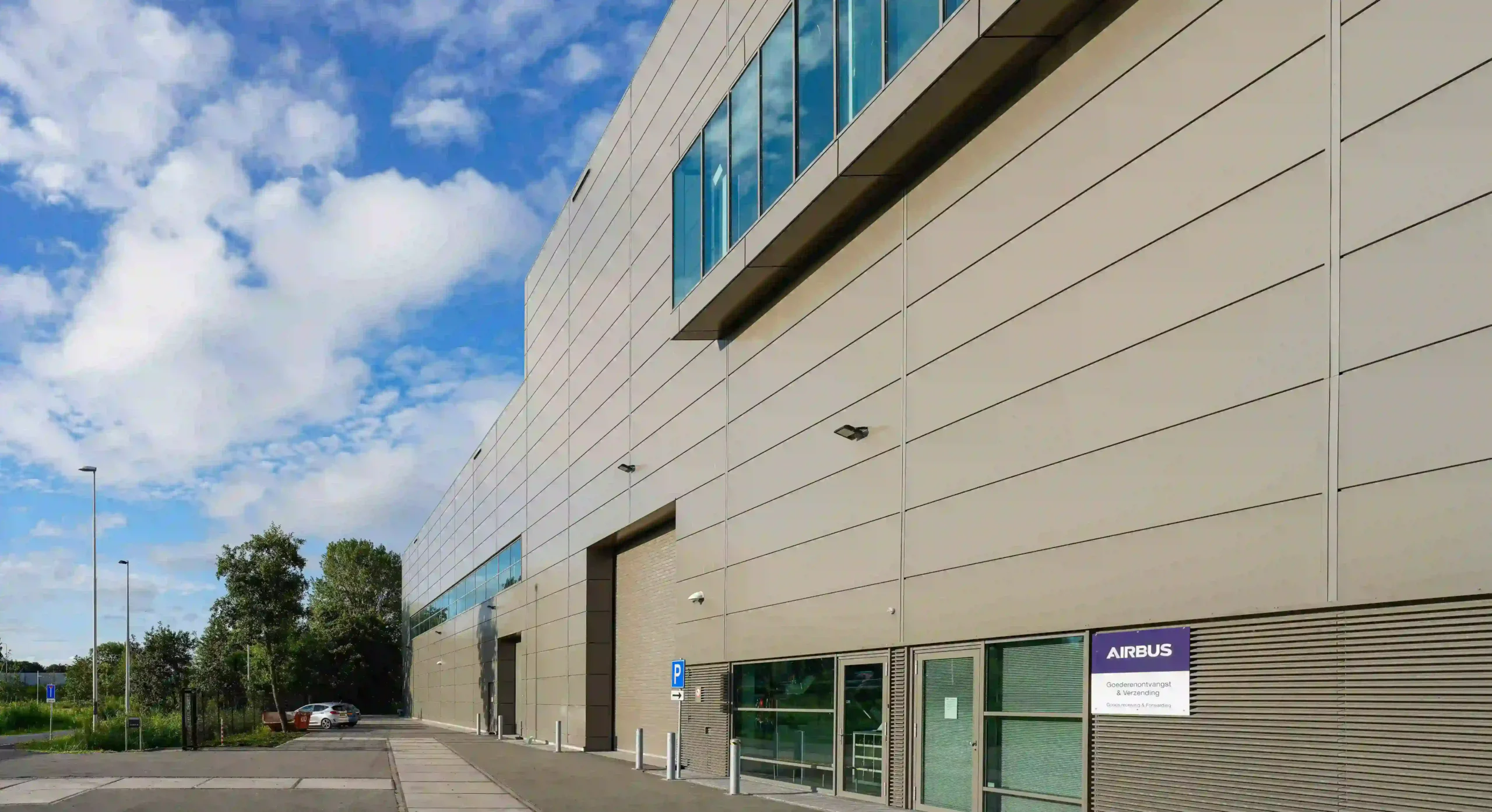 The exterior of a modern industrial building with an Airbus sign and a clear blue sky.