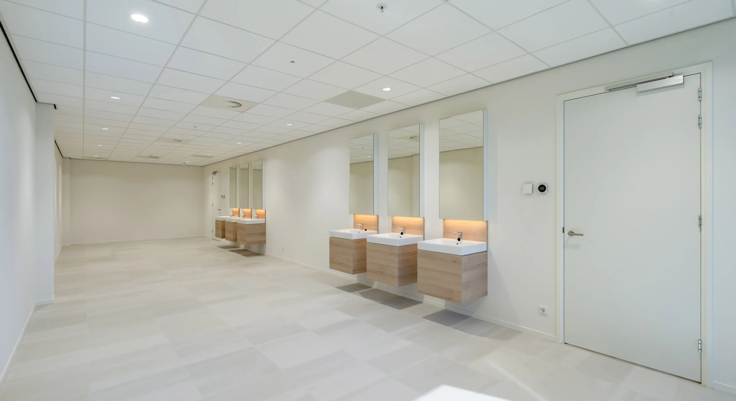 A spacious, modern restroom with multiple sinks and mirrors on the wall.