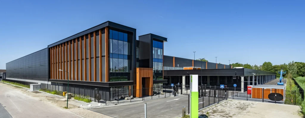 A modern industrial building with large windows and wooden accents under a clear blue sky.