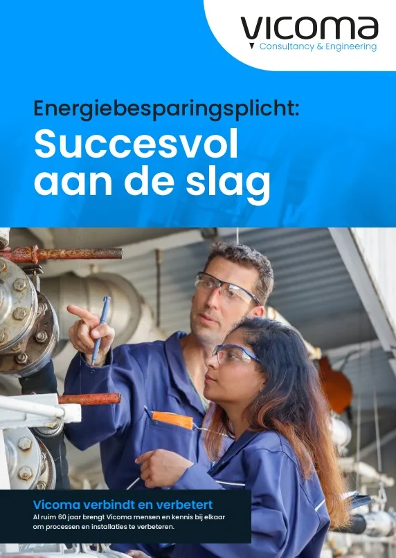 Two engineers in protective eyewear inspect industrial equipment.