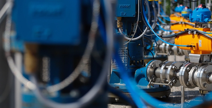 A row of industrial instrumentation with blue and orange machinery connected by cables.