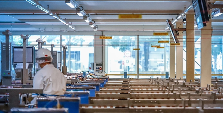 A worker wearing a hard hat in a factory setting focused on mechanical and structural steel production.