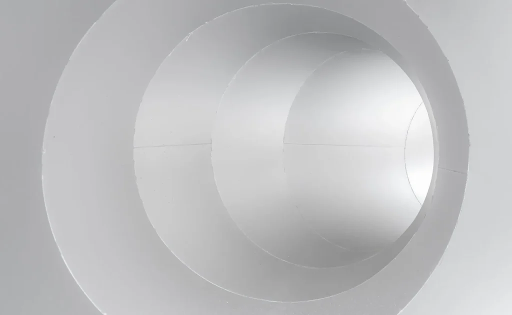 The image shows the interior of a white, circular pipe with concentric layers.