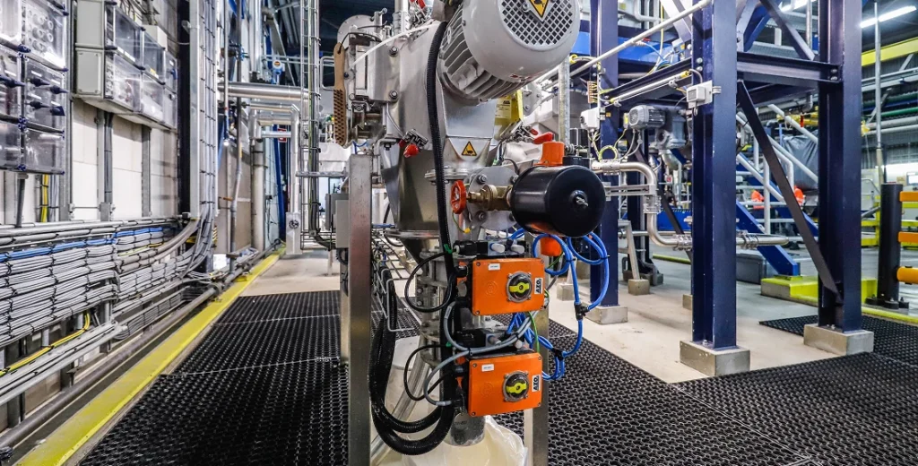 Industriële machinerie en leidingen in een productieomgeving.