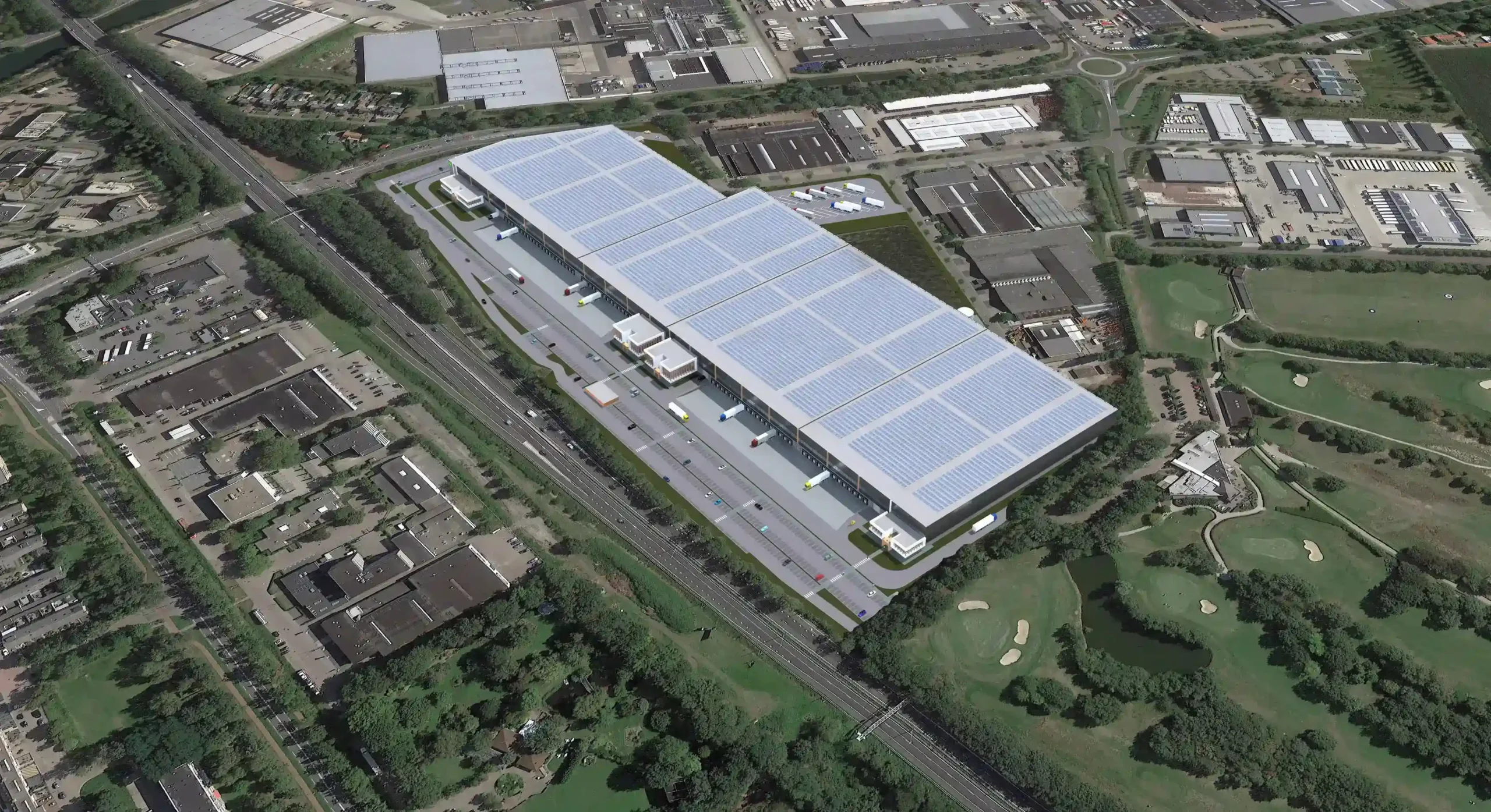 Aerial view of a large industrial warehouse with solar panels on the roof surrounded by greenery and adjacent buildings.
