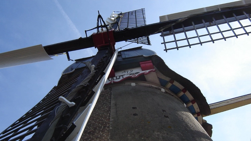 A low-angle view of a traditional Dutch windmill in Wageningen against a clear blue sky.