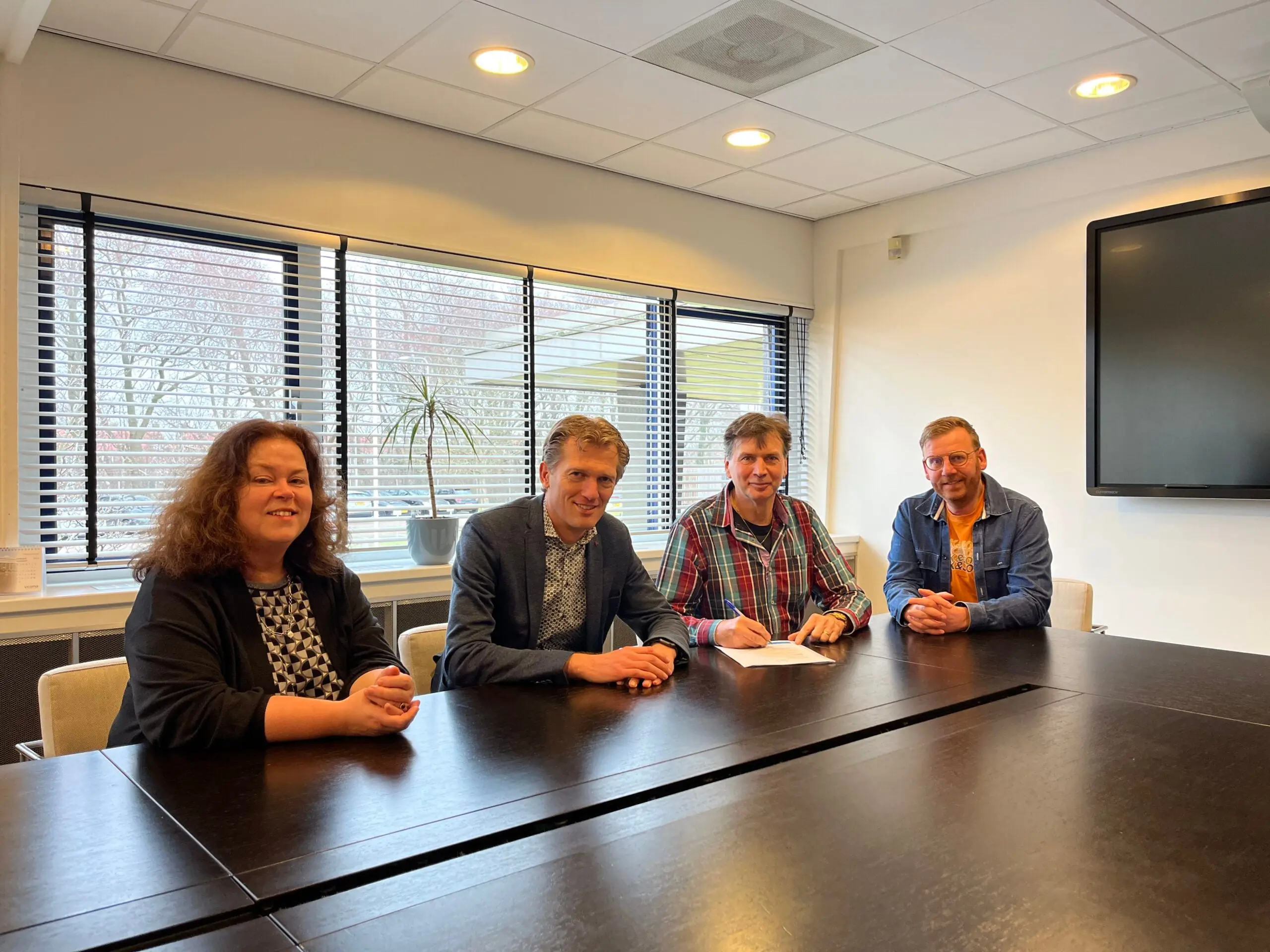 Four people sitting at a conference table in a meeting room.